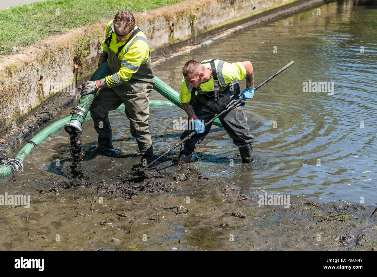 Arbeitnehmer mit einer Saugpumpe Schlamm und Schlick in einem See zu entfernen. Stockfoto