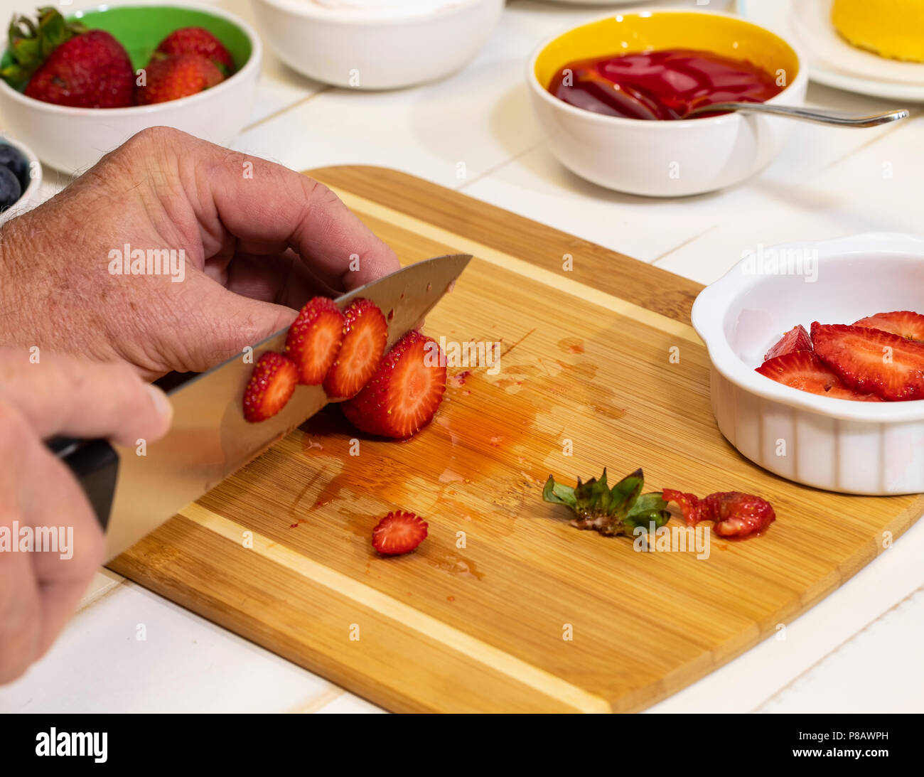 Man schneiden frische Erdbeeren auf einem Schneidebrett. Stockfoto