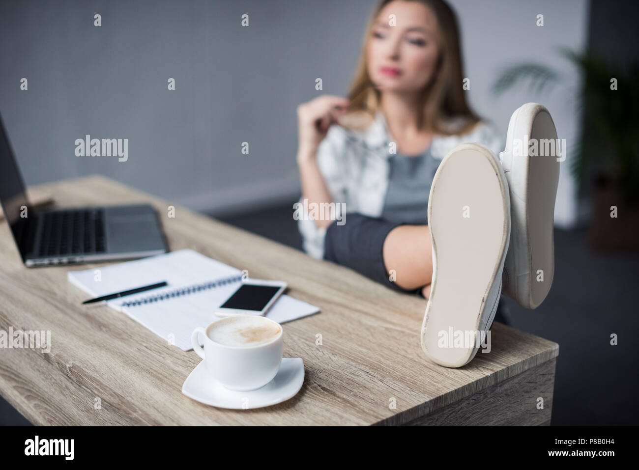 Junge Geschäftsfrau entspannen am Arbeitsplatz mit den Füßen am Tisch Stockfoto