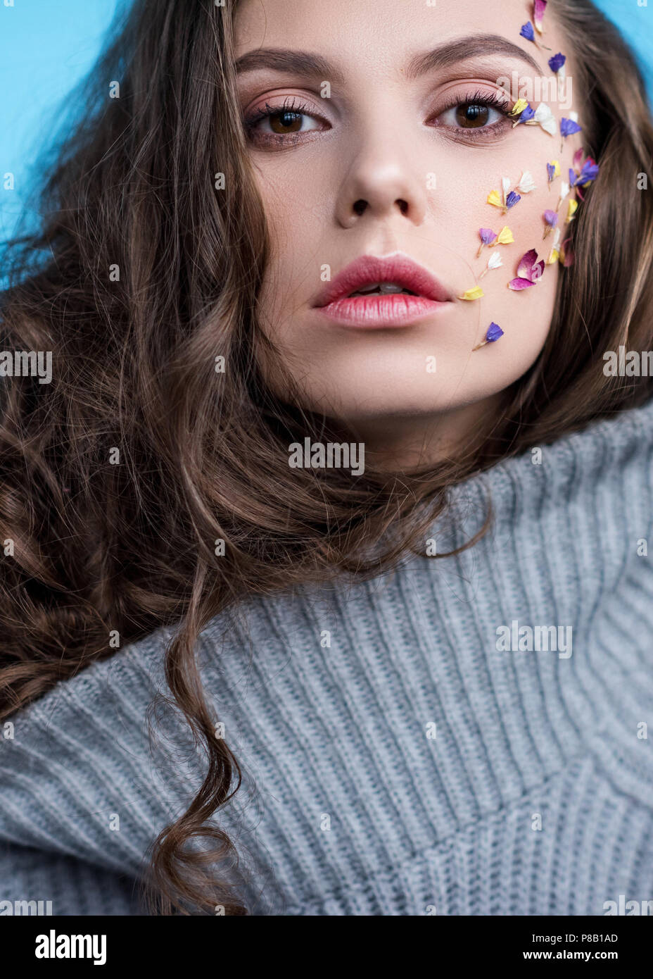 Nahaufnahme Porträt der Frau in warmen graue Strickjacke mit Blumen zu Gesicht Stockfoto