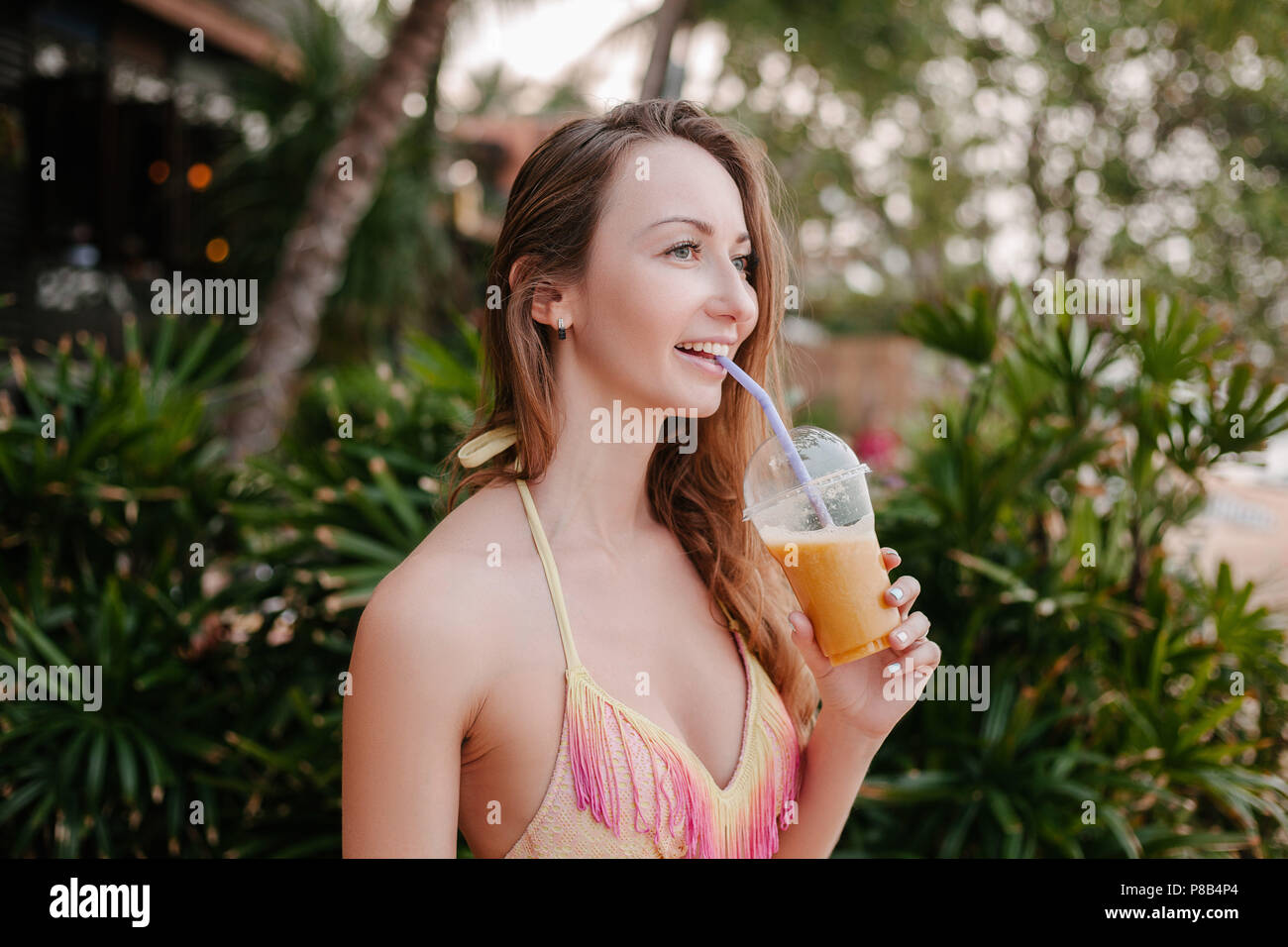 Lächelnd attraktive Mädchen im Bikini Top Cocktail trinken Stockfoto