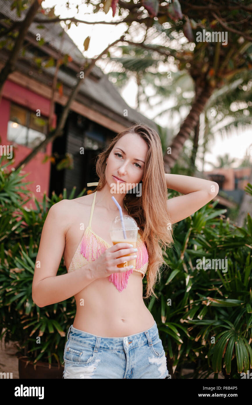 Attraktive Mädchen im Bikini Top holding Cocktail und Kamera Stockfoto