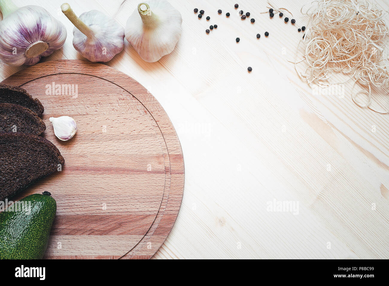Essen Hintergrund mit frischen Bioprodukten Avocado, Roggenbrot und Knoblauch auf Holzplatte Stockfoto