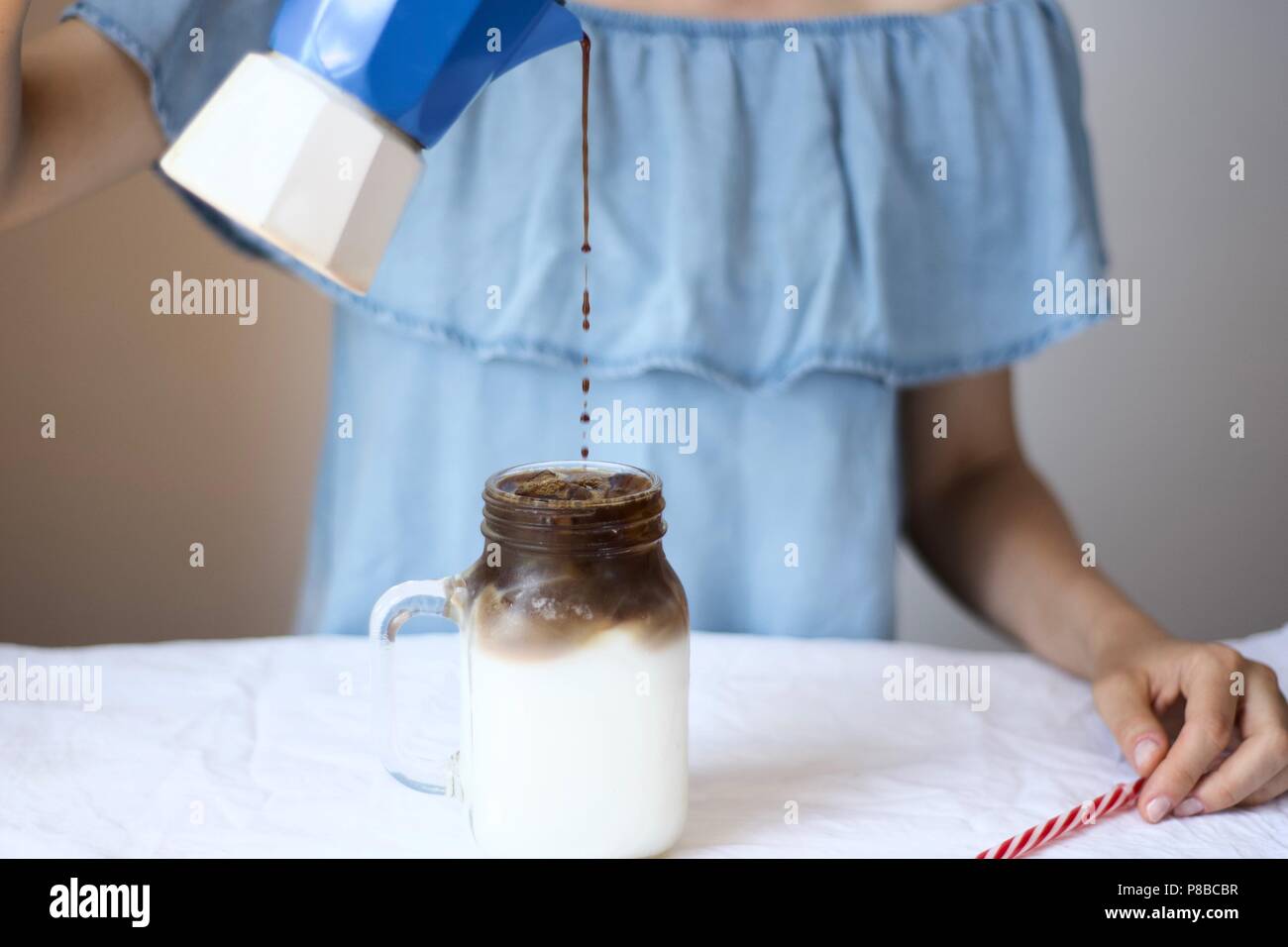 Eine Frau, die junge Mädchen in Sommer Frühstück, Eiskaffee in einem Marmeladenglas Becher mit Stroh mit einem italienischen Mokka Stockfoto