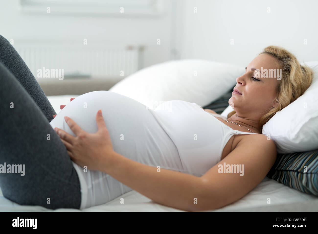 Schwangere blonde Frau Kontraktionen zu Hause in Stockfoto
