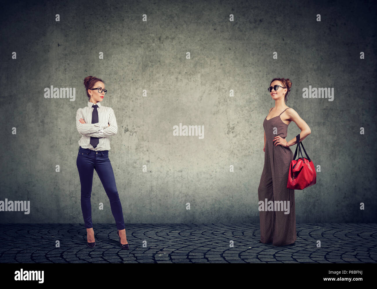 Junge Frau in zwei verschiedenen Outfits, informelle und formelle Kleidung für Hausfrau und Geschäftsfrau auf grauem Hintergrund Stockfoto