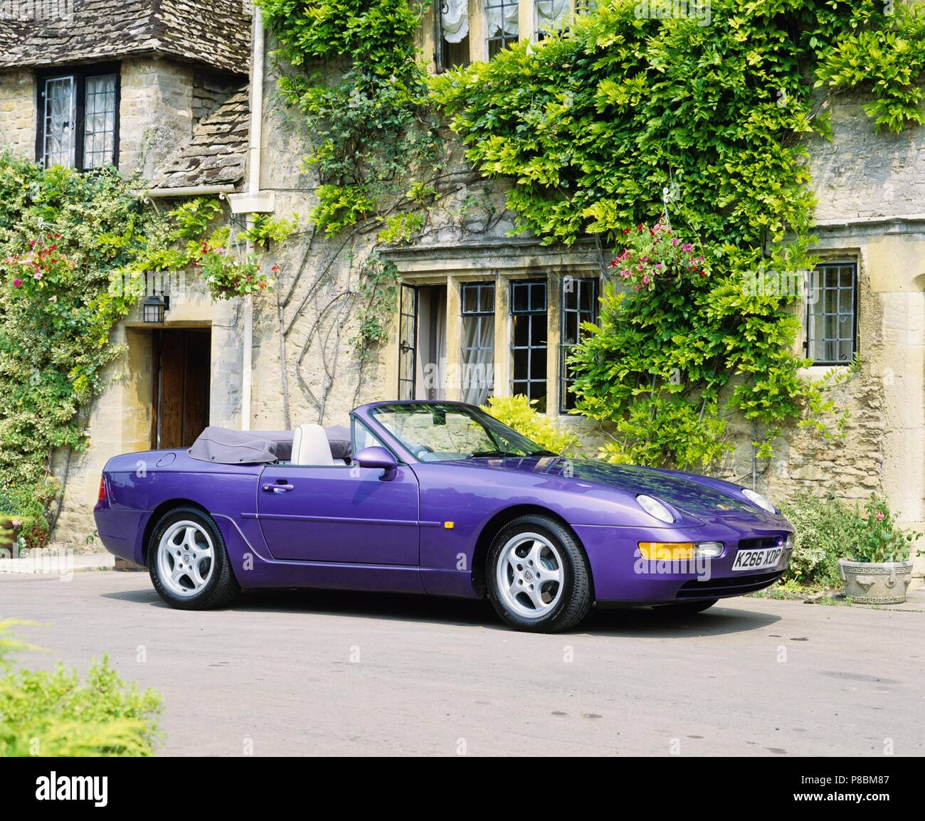 Porsche 968 Cabrio - 1993 Modell Jahr in Amaranth Violett Lack in ländlicher Umgebung Vorder- und Seitenansicht mit Dach unten Stockfoto