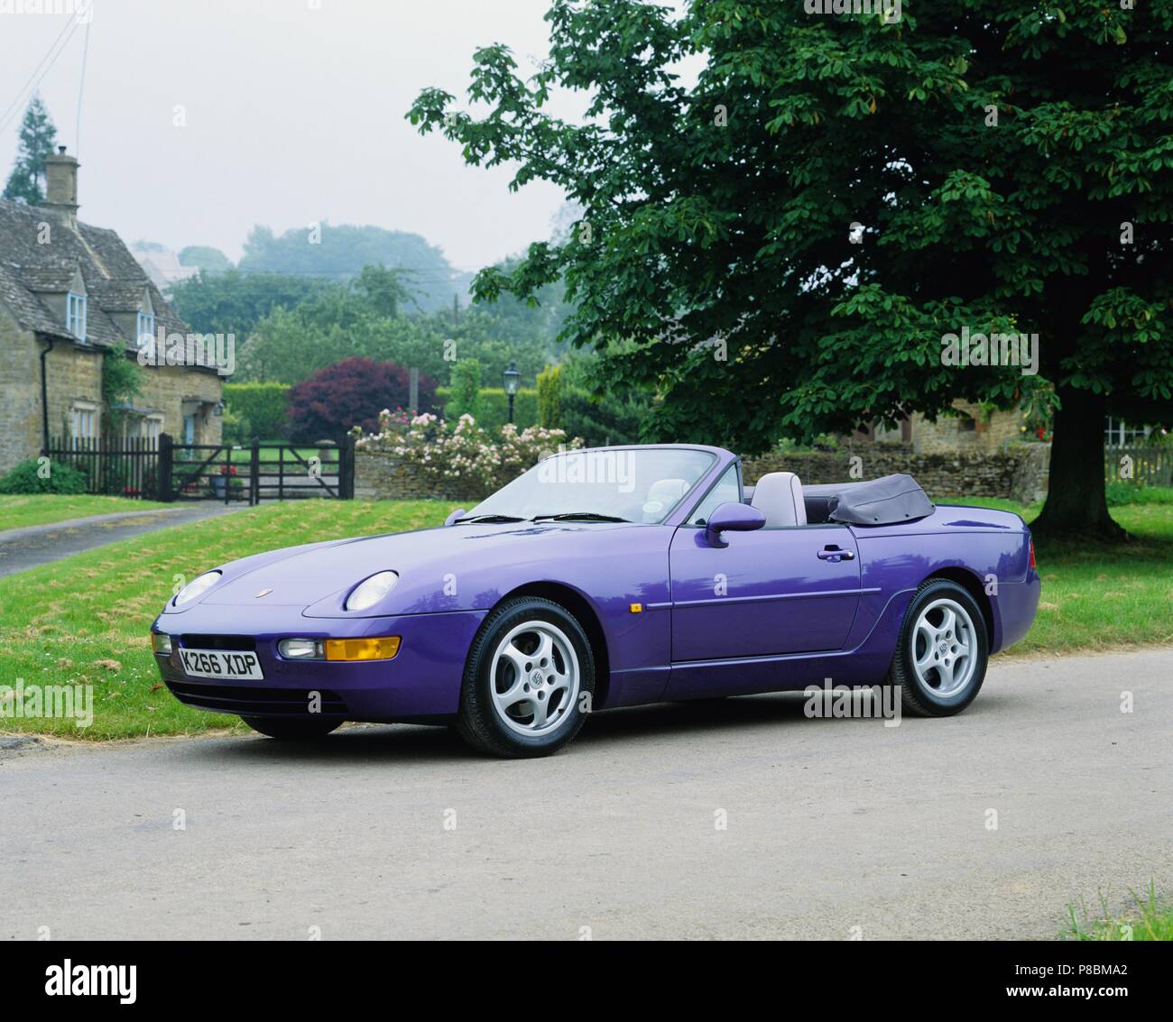 Porsche 968 Cabrio - 1993 Modell Jahr in Amaranth Violett Lack in ländlicher Umgebung Vorder- und Seitenansicht mit Dach unten Stockfoto