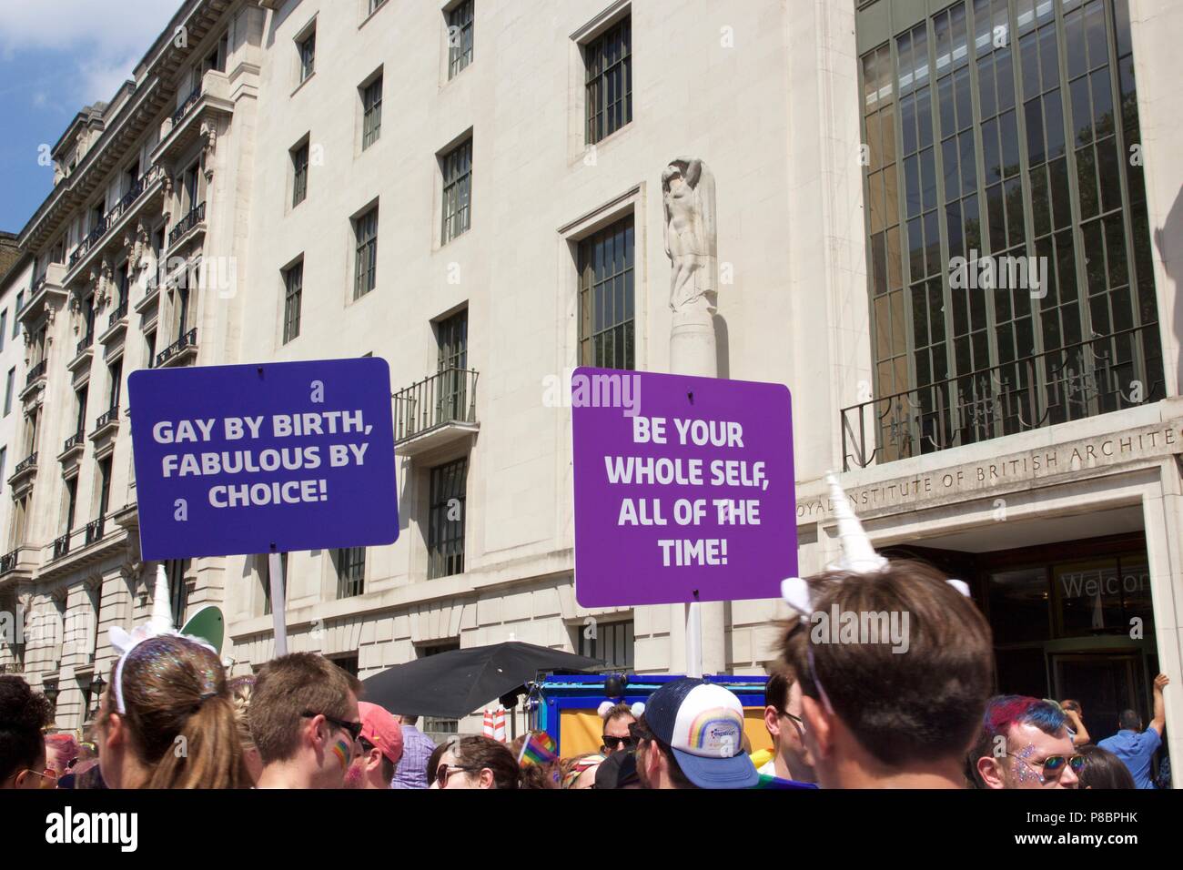 Plakate mit der Aufschrift "Gay durch Geburt' und 'Ihr ganzes Selbst' im Pride Parade in London 2018. Stockfoto