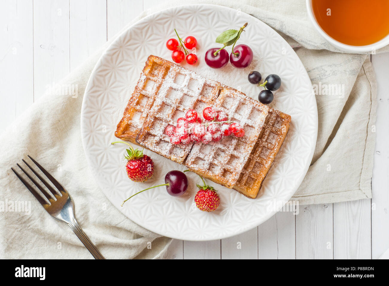 Selbstgemachte Waffeln mit Sommer Beeren auf einem Teller. Eine Tasse ...