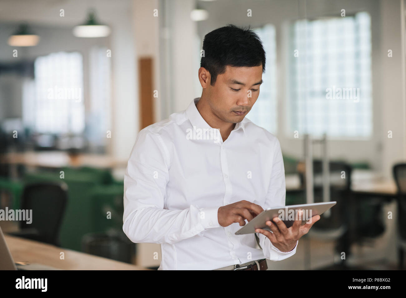 Asiatische Geschäftsmann mit einem Tablet in einem Büro konzentriert Stockfoto