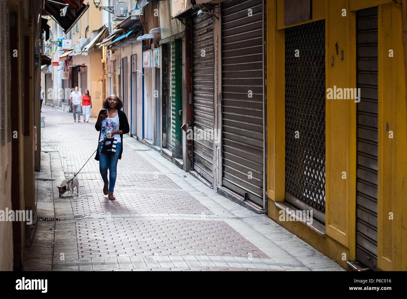 Frau wandern Hund auf einer Straße in der Altstadt von Nizza, Frankreich Stockfoto