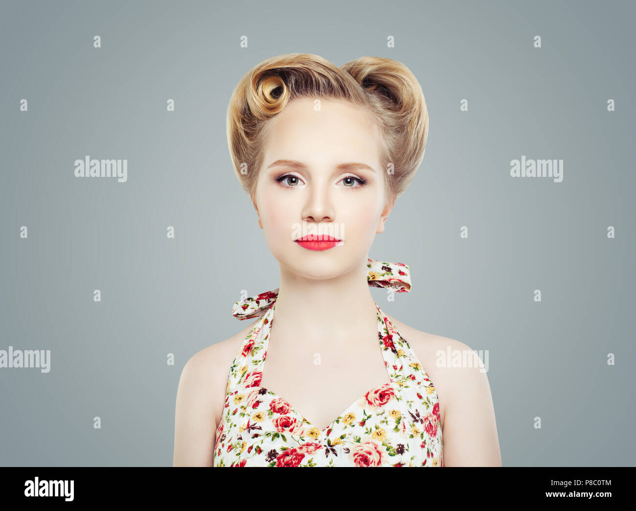 Junge blonde Frau mit Vintage Retro Pinup Frisur und Make-up gegen graue Wand Hintergrund Stockfoto