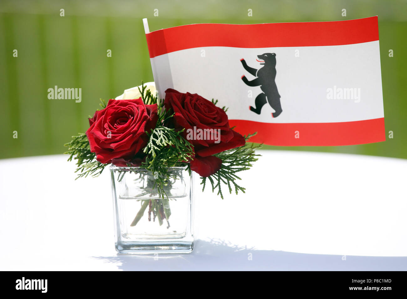 Hoppegarten, Deutschland, Flagge des Landes Berlin und rote Rosen in einer kleinen Vase Stockfoto
