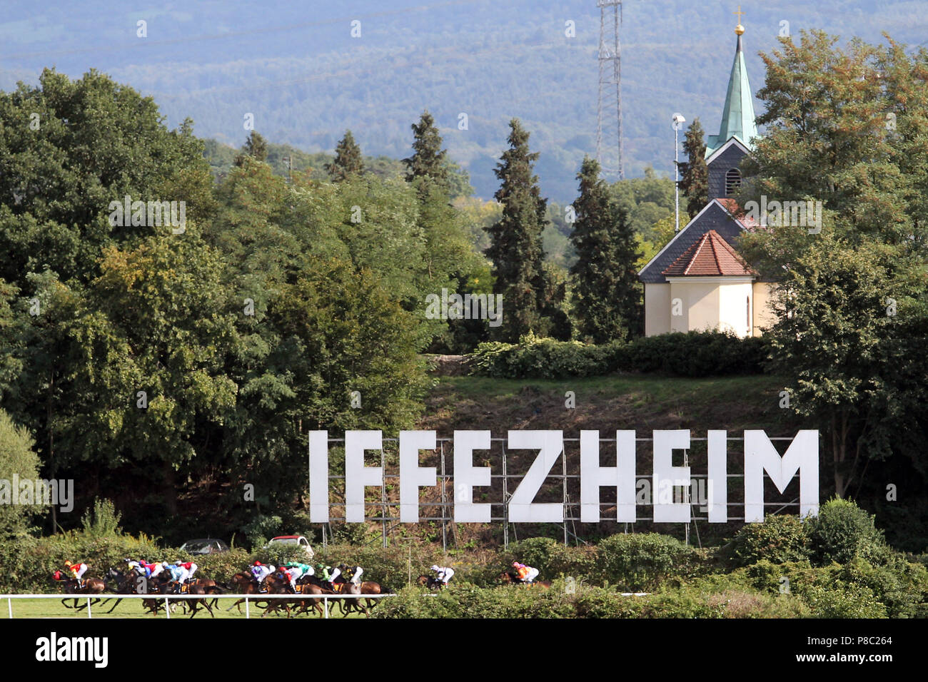 Iffezheim, Deutschland, Pferde und Jockeys unter dem Iffezheim Schriftzug und die Kapelle Stockfoto