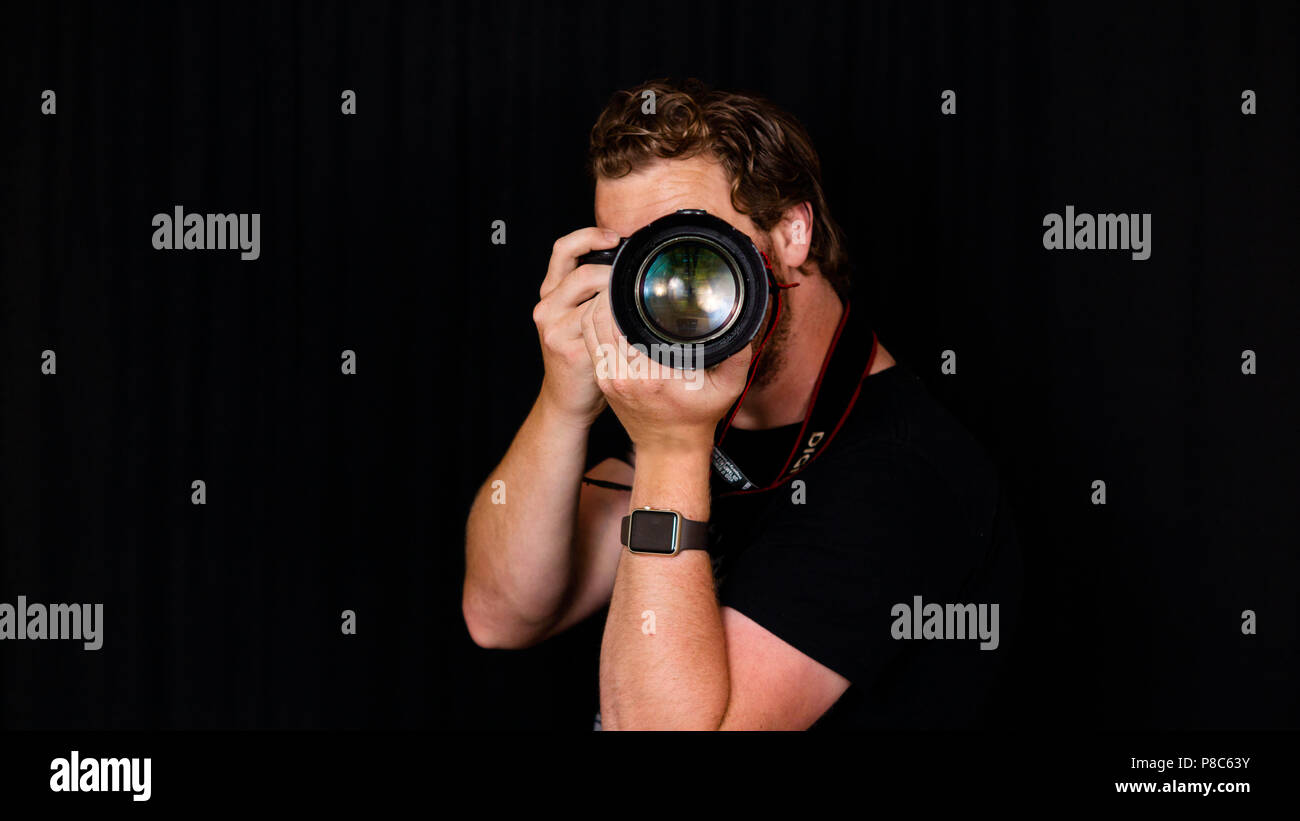 Ein professioneller Fotograf hält seine Kamera nah an seinem Gesicht. Stockfoto