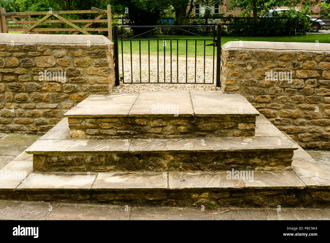 Tiered Steinstufen führen zu einem metallischen Seite Eingangstor zu einer privaten Immobilie in Wiltshire England Großbritannien Stockfoto