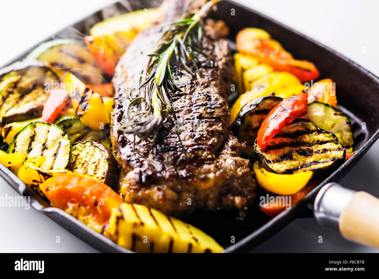Griechische organische Lamm Steak mit gegrilltem Gemüse und Kräuter in der heißen Pfanne Stockfoto