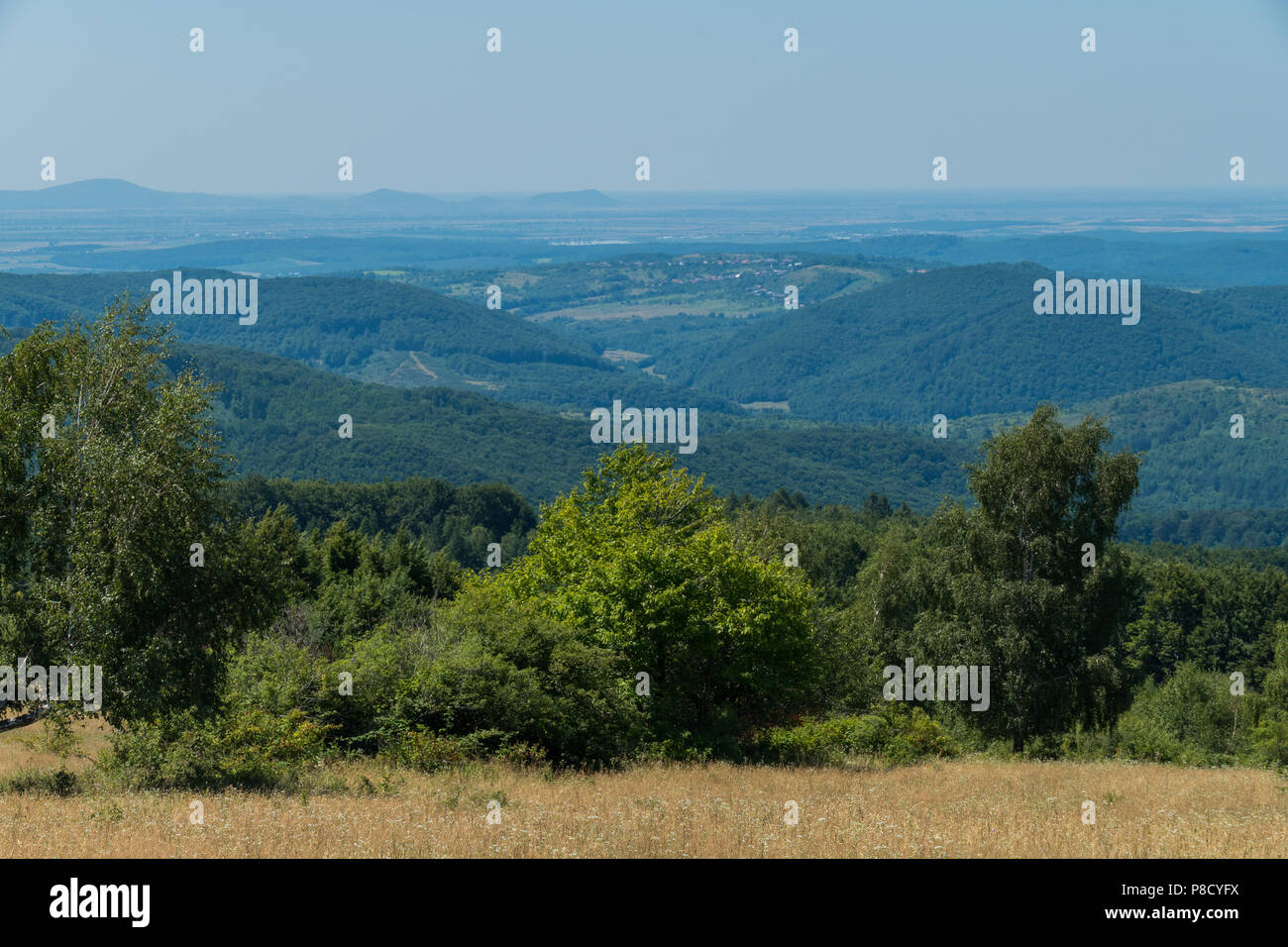 Landschaft von der Anhöhe in eine weit entfernte Stadt zwischen den grünen Bergen unter dem blauen Himmel. Für ihr Design Stockfoto