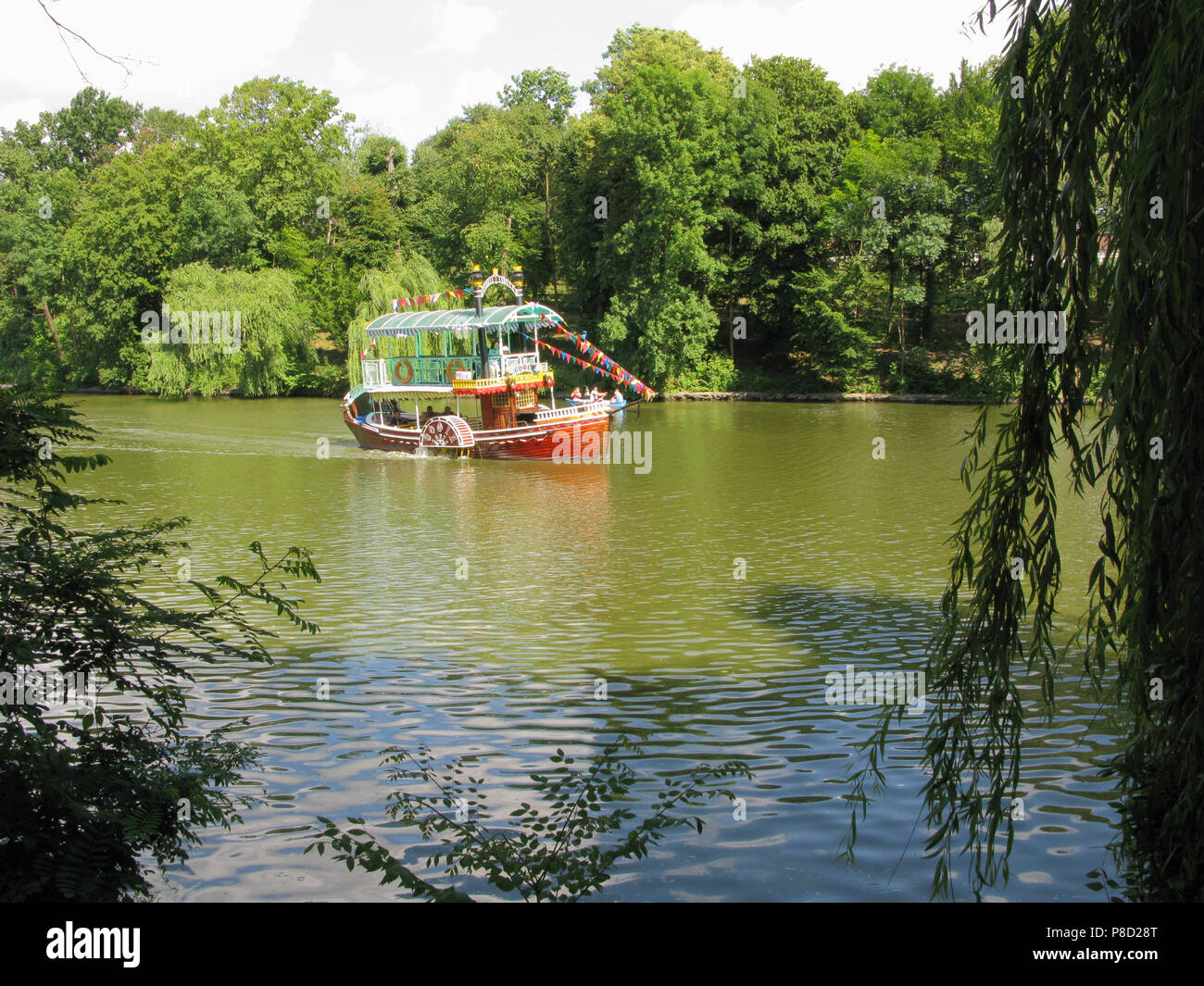 Ein 2-stöckiges Fluss Schiff sweeps rasch über die schwarzer Oberfläche vor dem hintergrund der grünen Park Zone. Für ihr Design Stockfoto
