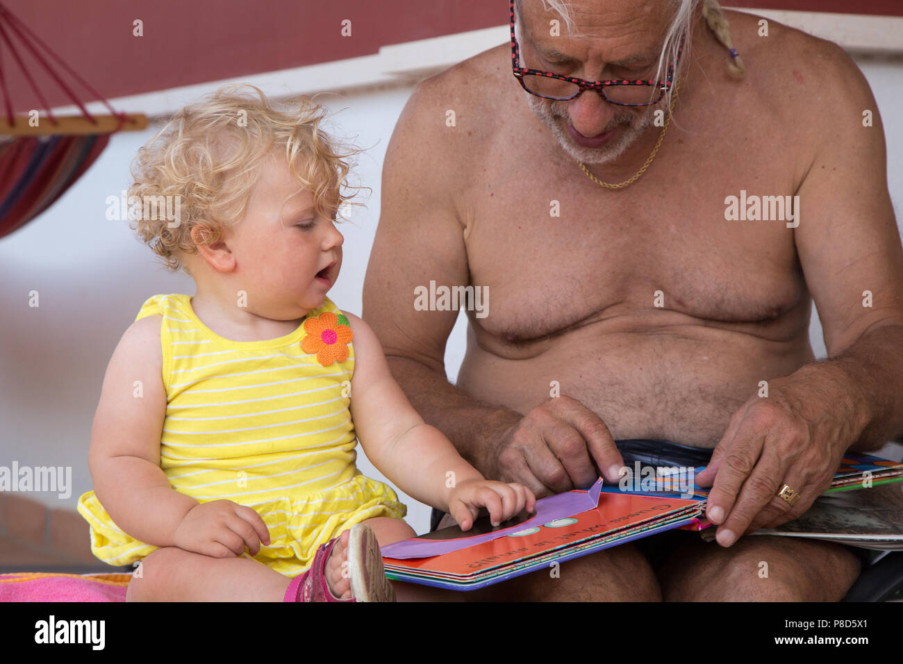Ein Großvater liest ein Buch mit seinem Kind ein Jahr alte Enkelin Stockfoto