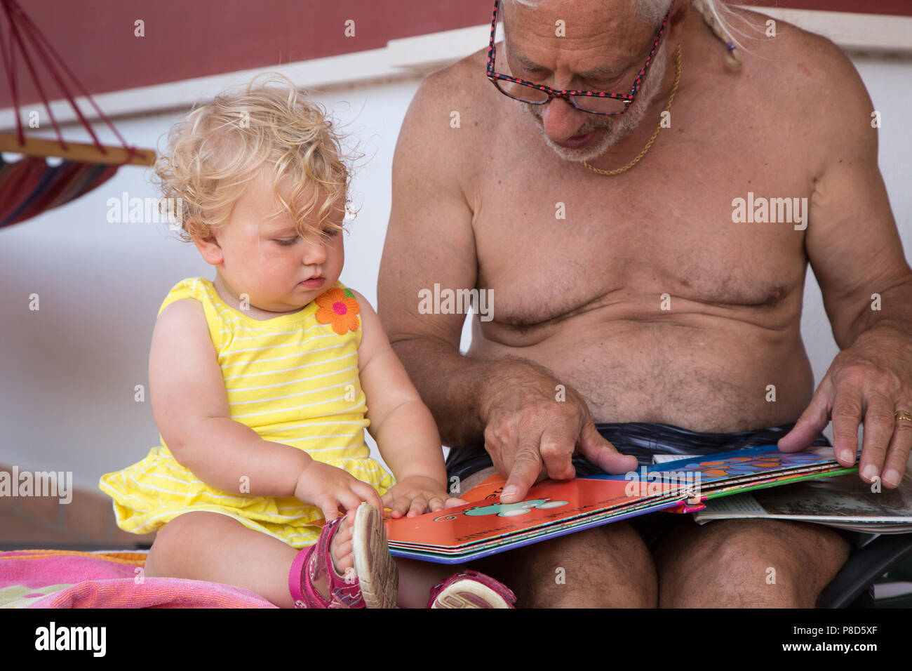 Ein Großvater liest ein Buch mit seinem Kind ein Jahr alte Enkelin Stockfoto