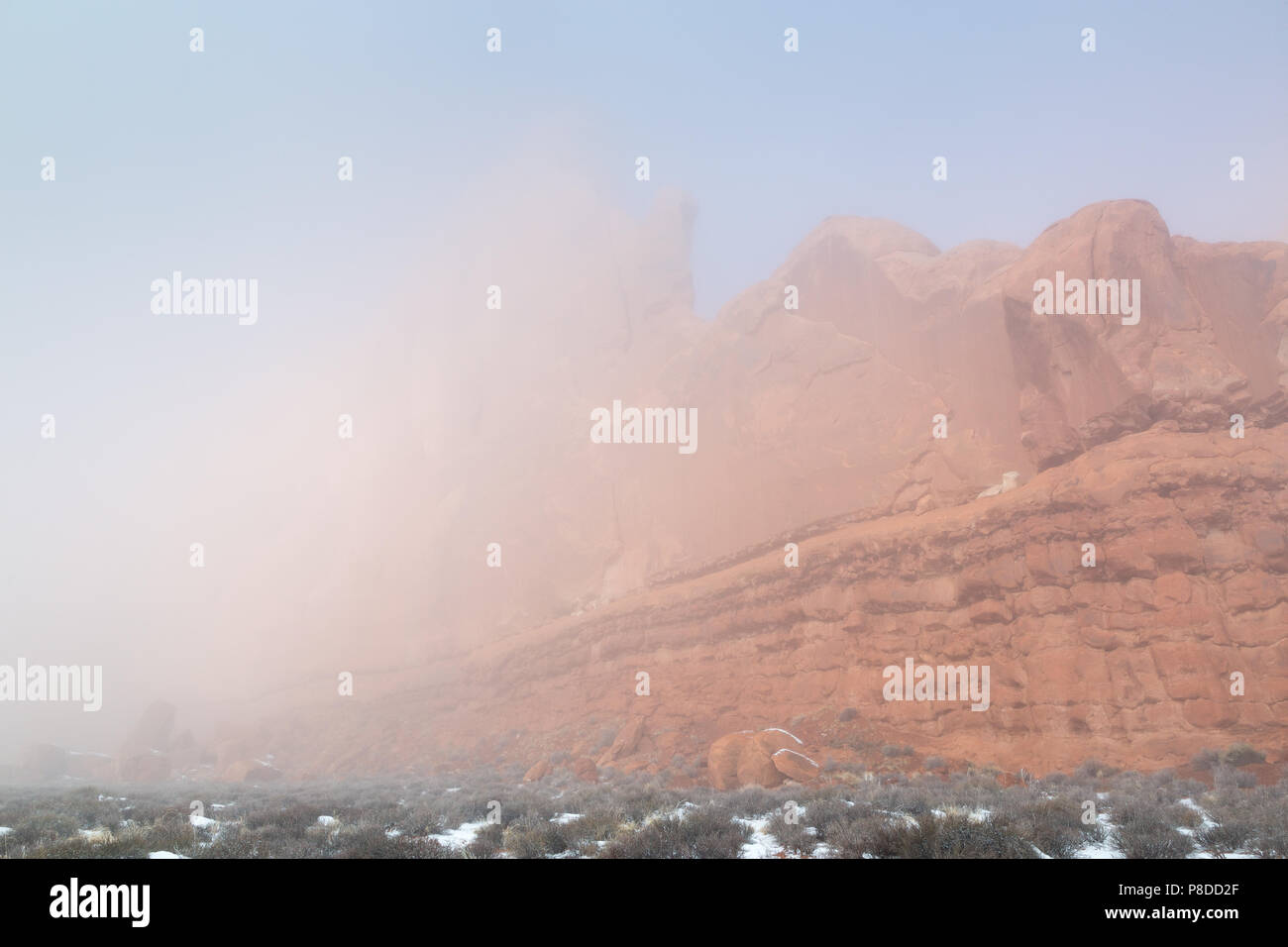 Eine große Sandstein Butte, die aus einem dichten Nebel an einem Wintermorgen. Arches National Park, Utah Stockfoto