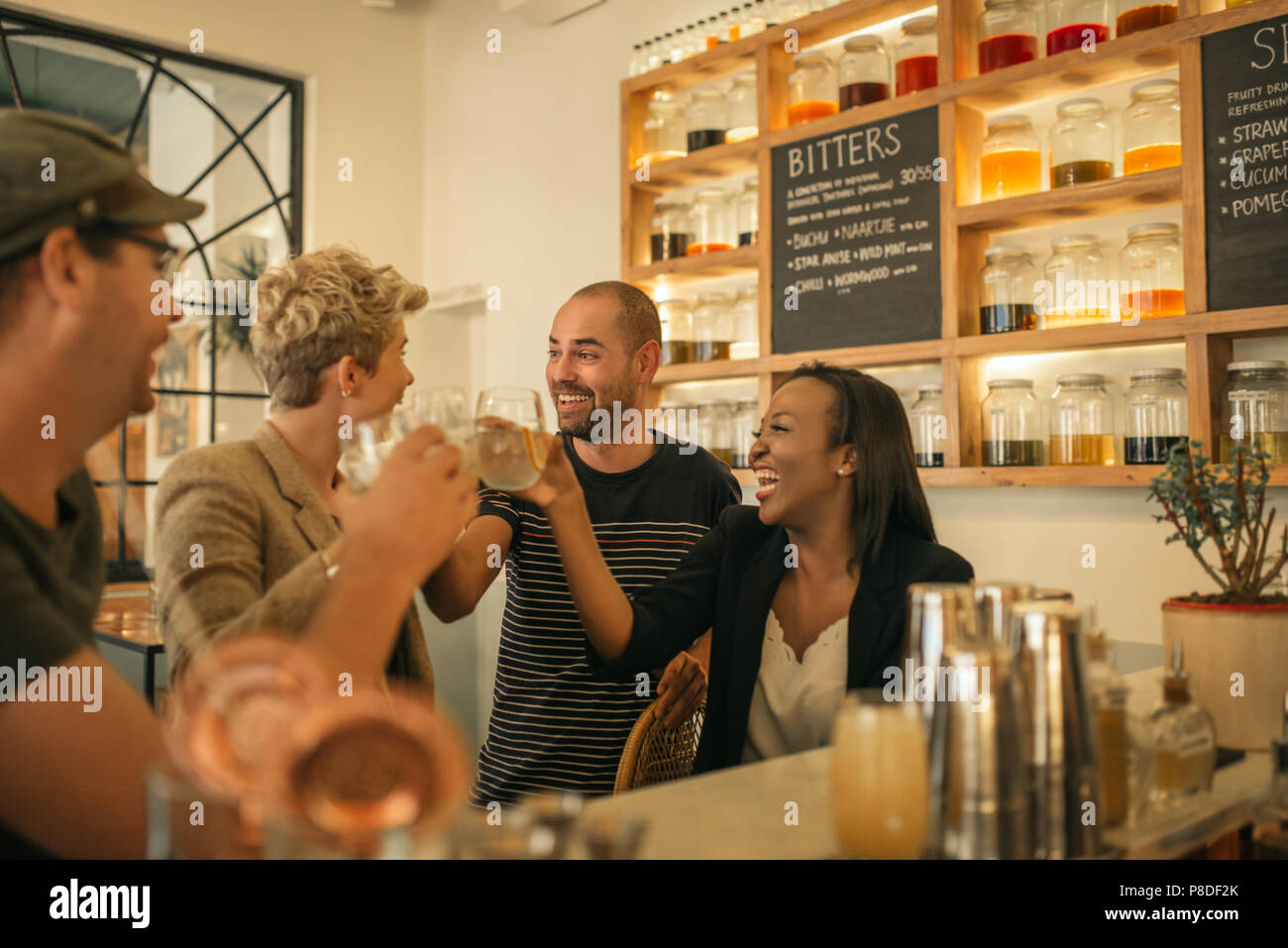 Lächelnd Freunde jubeln mit Getränken in einer angesagten Bar Stockfoto