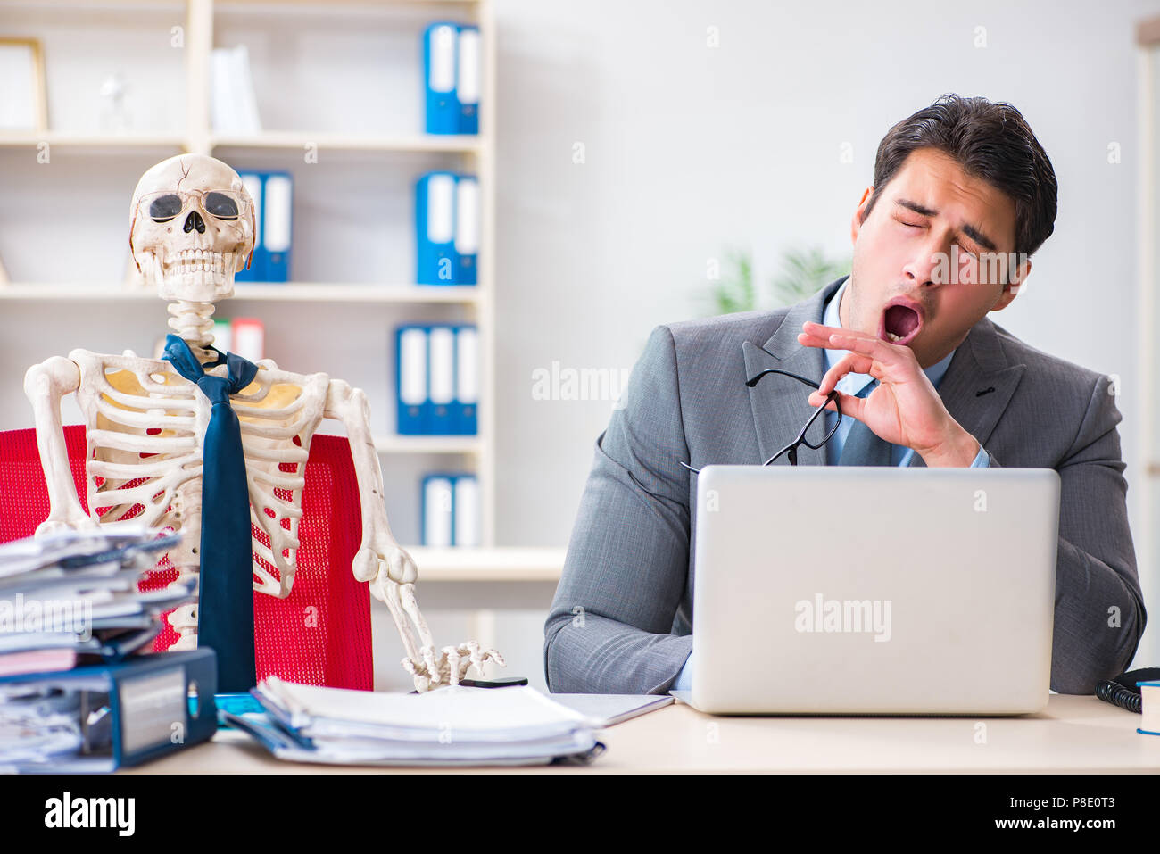 Unternehmer arbeiten mit Skelett im Büro Stockfoto