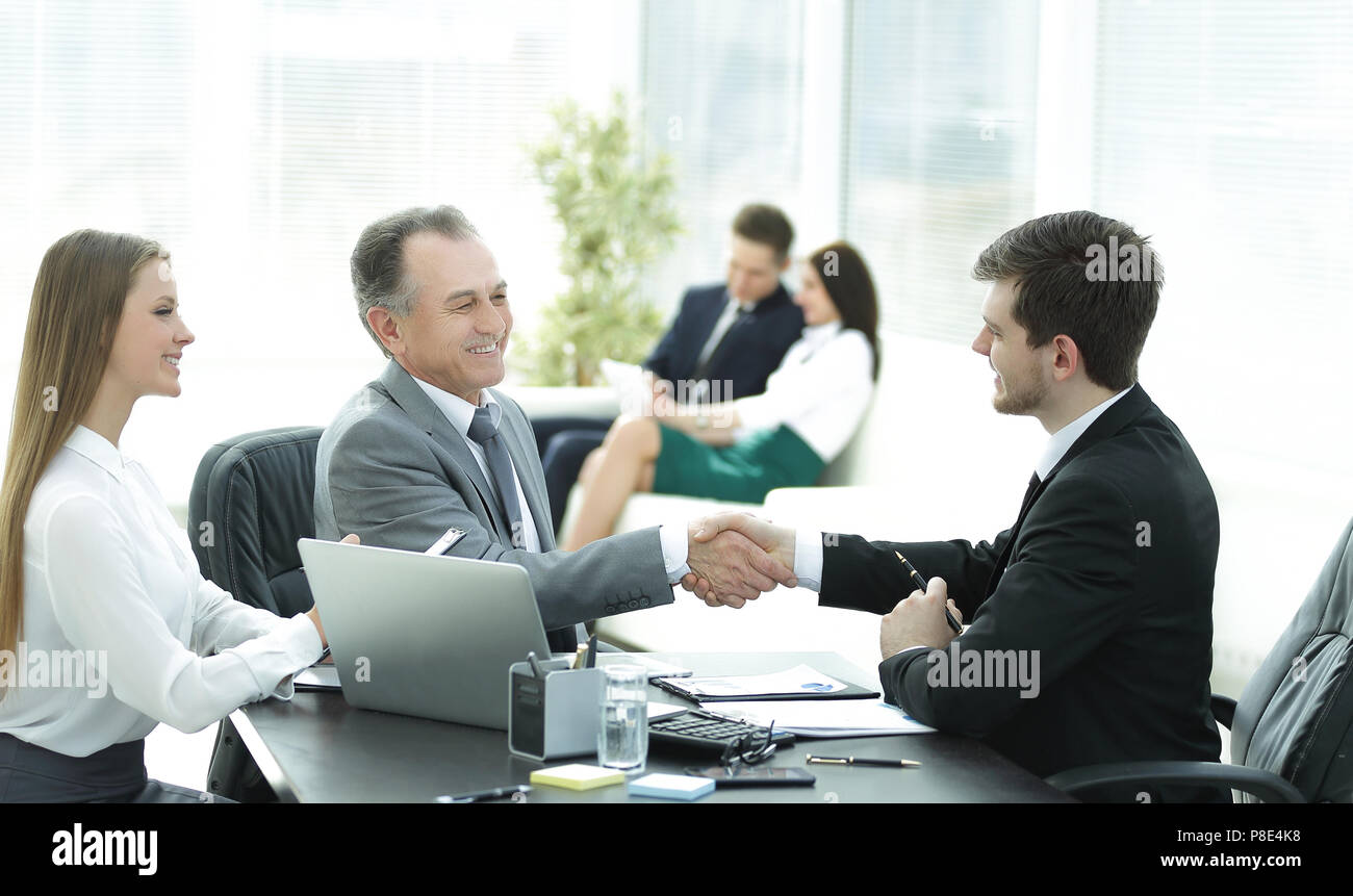 Handshake Geschäft Leute hinter einem Schreibtisch im Büro Stockfoto