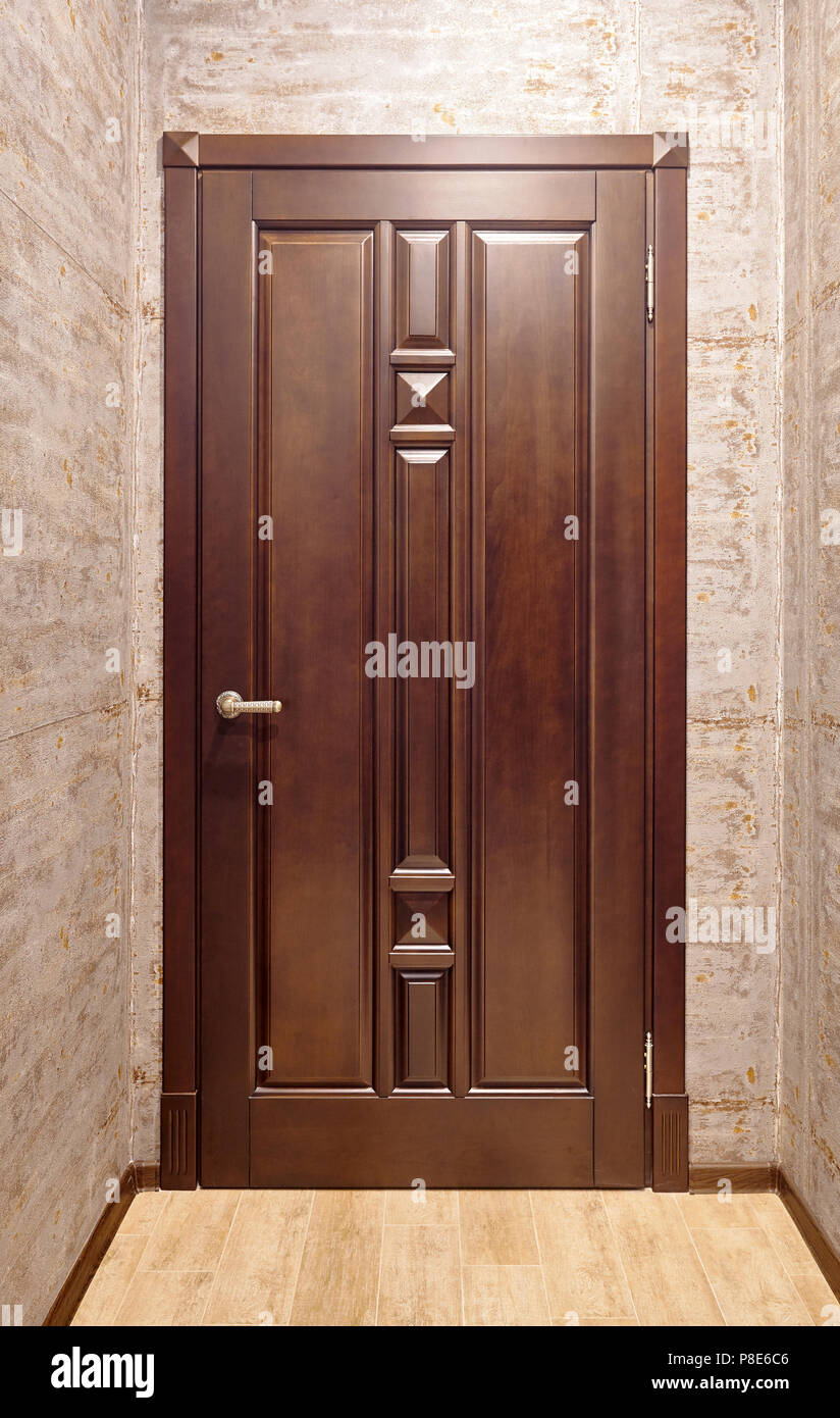 Braun Metall mit Holz- overlays Eingangstür mit Messing-griff im Korridor mit Stock in Beigetönen Fliesen- Stockfoto