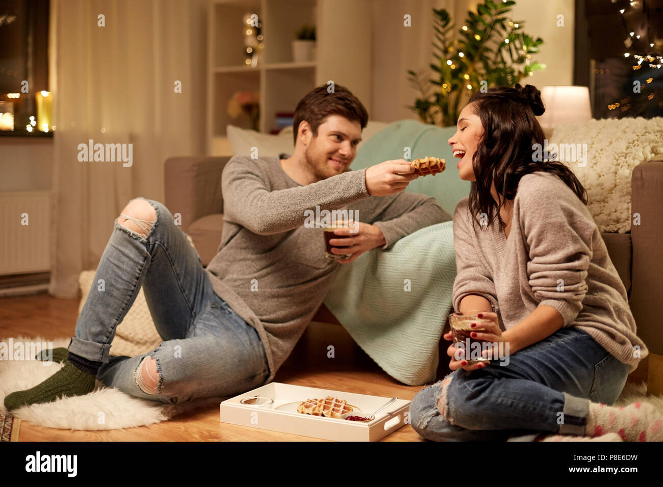 Glückliches Paar essen Waffeln mit Kakao zu Hause Stockfoto