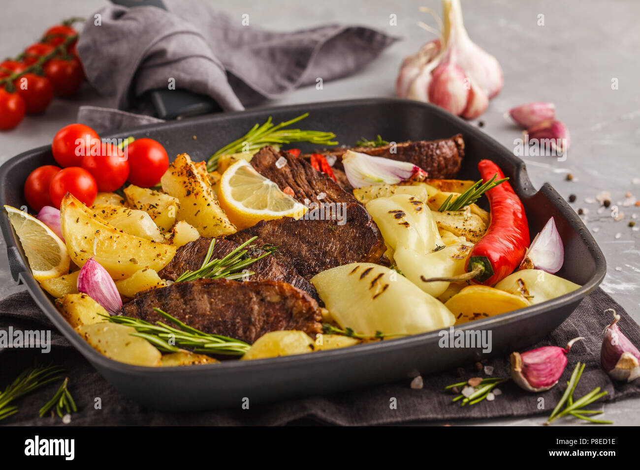 Rindersteaks vom Grill mit gebackenen Kartoffeln und Gemüse in einer ...