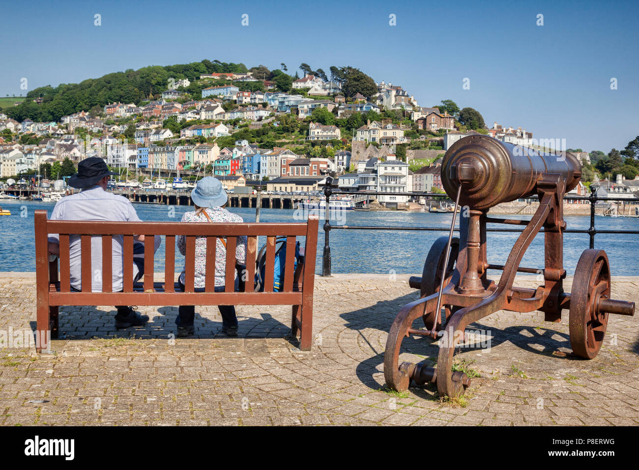 23. Mai 2018: Dartmouth, Devon, UK-Paar auf einer Bank sitzen neben einer alten Kanone, mit Blick auf den Fluss Dart. Stockfoto