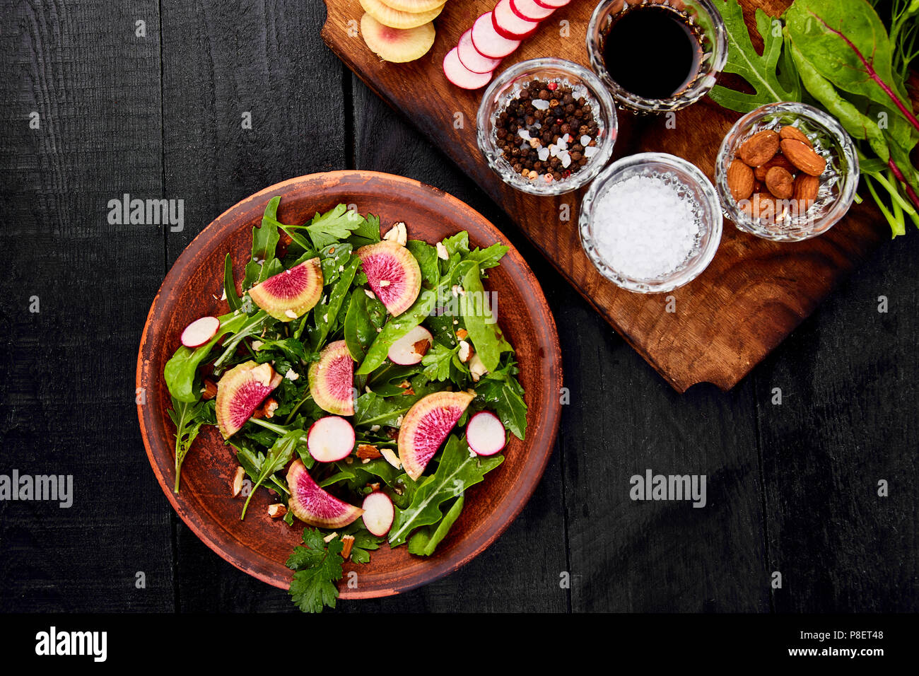 Zutat und Salat braunen-mix Blatt auf Holz Schneidebrett. Radieschen, Salat, Mangold, Petersilie, Dill, Rucola, Mandeln, Salz, lecker, Balsamico, Stockfoto