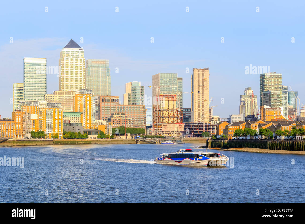 Ein Kreuzfahrtschiff auf der Londoner Themse mit Canary Wharf Stadtbild im Hintergrund Stockfoto