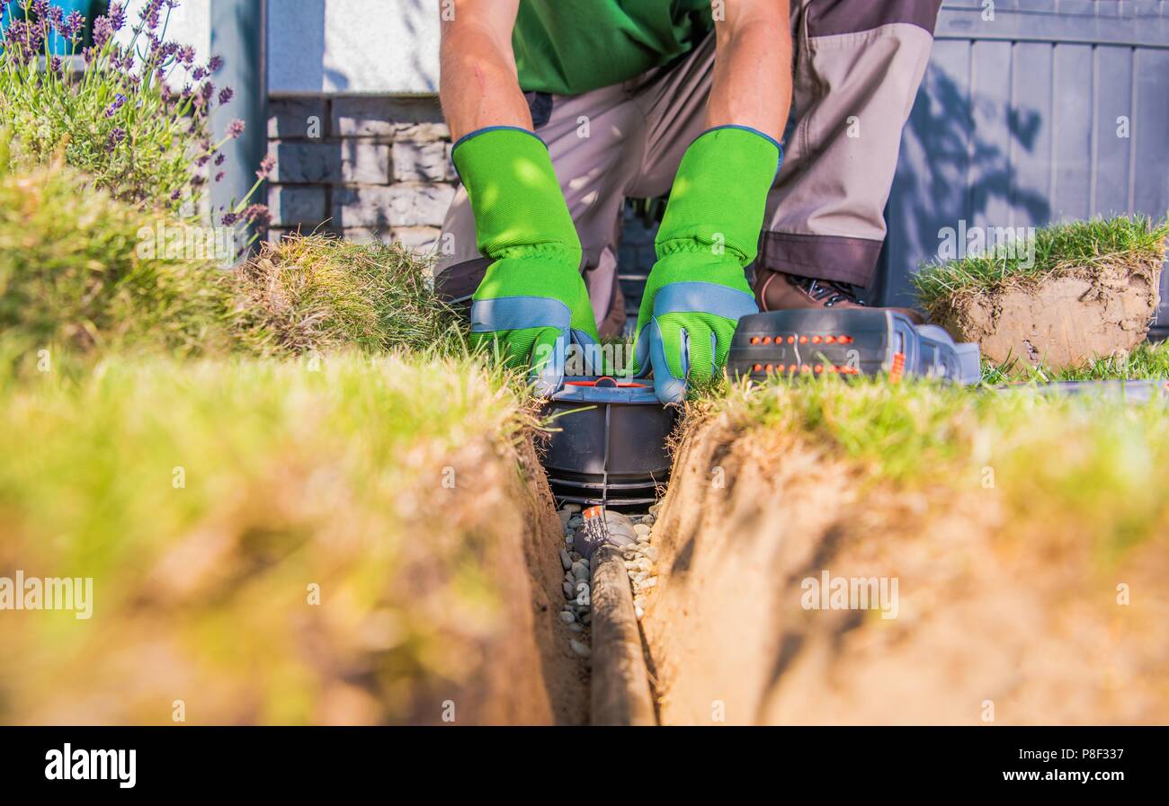 Gärtner Gebäude Hinterhof Gartenbewässerung Systeme. Automatische Rasensprenger Installation durch Techniker. Stockfoto