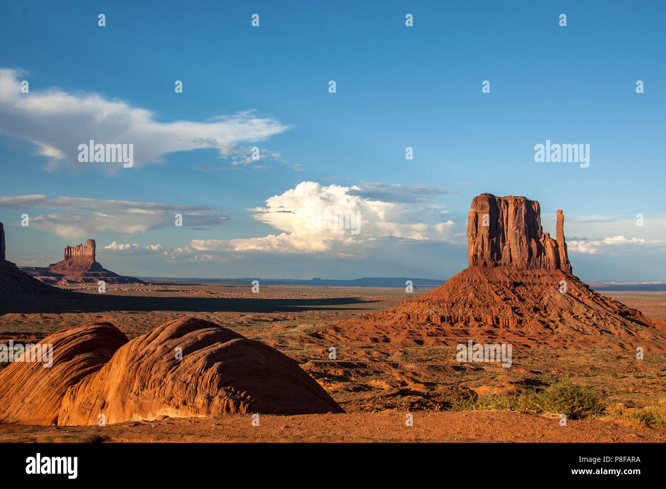 Mit späten Nachmittag haufenwolken Gebäude am Horizont, roter Sandstein buttes von Monument Valley steigen über flachen Ebenen der Navajo Nation land Stockfoto