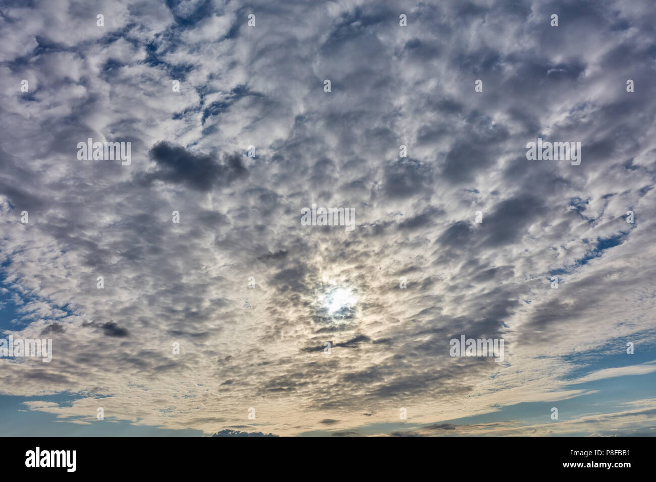 Viele Wolken und Sonne am Himmel bei Sonnenuntergang Stockfoto