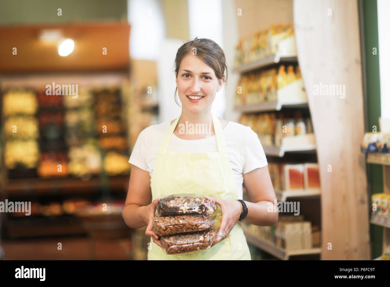 Lächelnde Verkäuferin holding Beutel der Muttern Stockfoto
