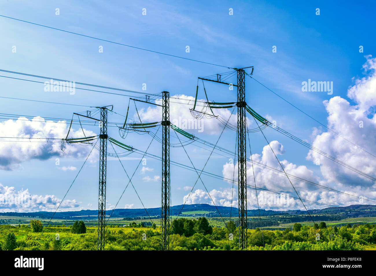 Hohe Spannung Sendemasten über blauen Himmel. Elektrische Energie Draht auf die ländliche Landschaft Hintergrund. Stockfoto