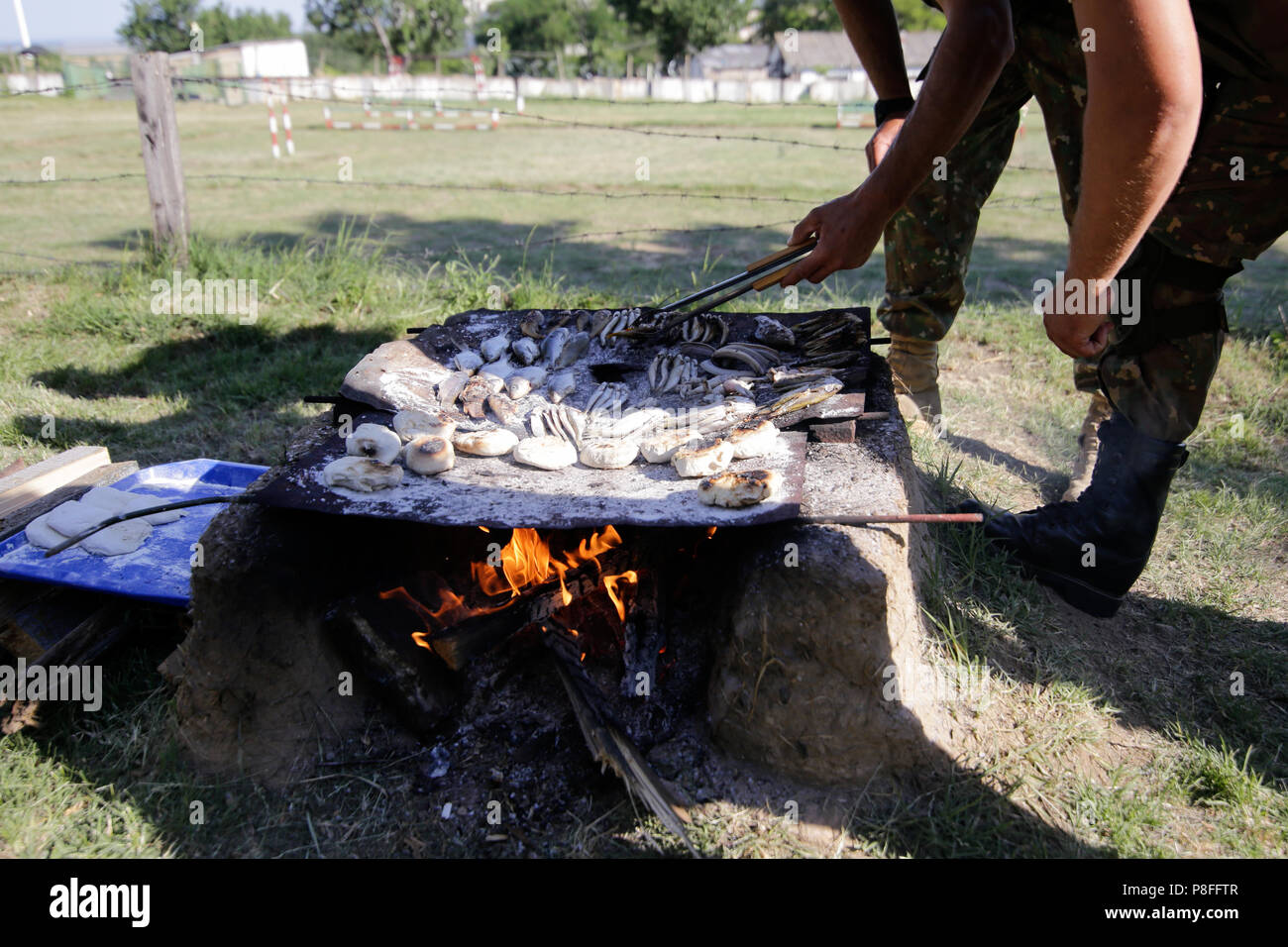 Die Soldaten bereiten Mahlzeiten auf einem handgefertigten Grill am offenen Feuer, Holz zu einem Survival Camp. Sie kochen Wasser Schlangen, Fische, Frösche und Brot. Stockfoto
