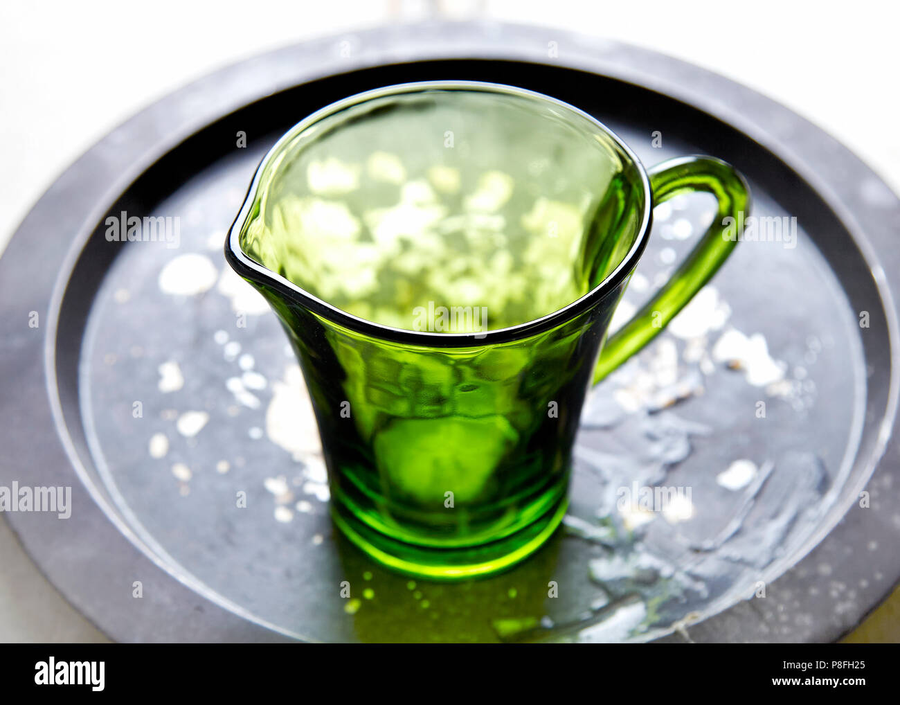 Grünes Glas Kanne auf einer beunruhigten Metallplatte Stockfoto