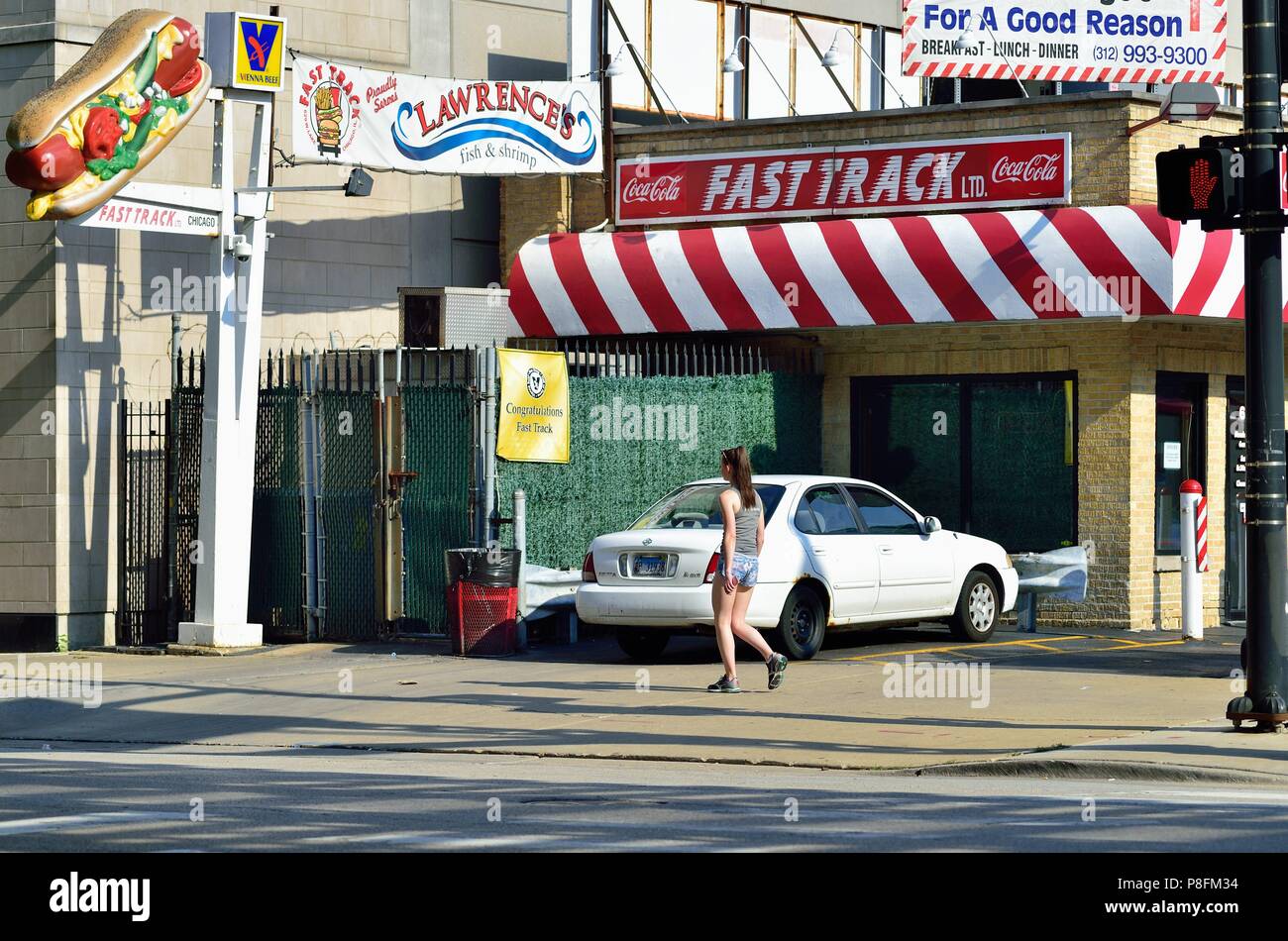 Chicago, Illinois, USA. Einsamer Fußgänger gehen hinunter Lake Street und vorbei an einem lokalen nighborhood Hot Dog stand und Diner. Stockfoto