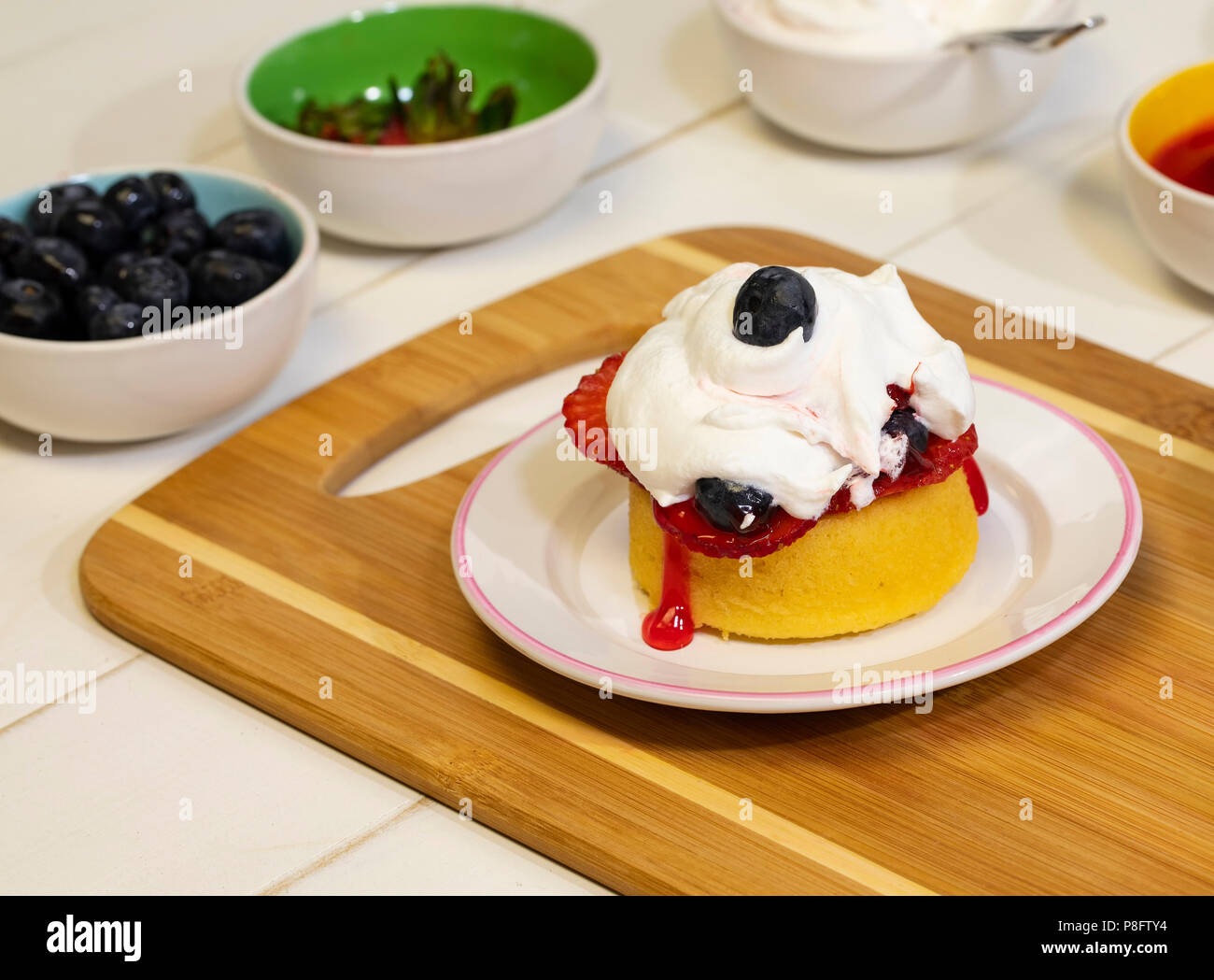 Vorbereitung shortcake Dessert mit frischen Erdbeeren, Blaubeeren, und Schlagsahne. Stockfoto