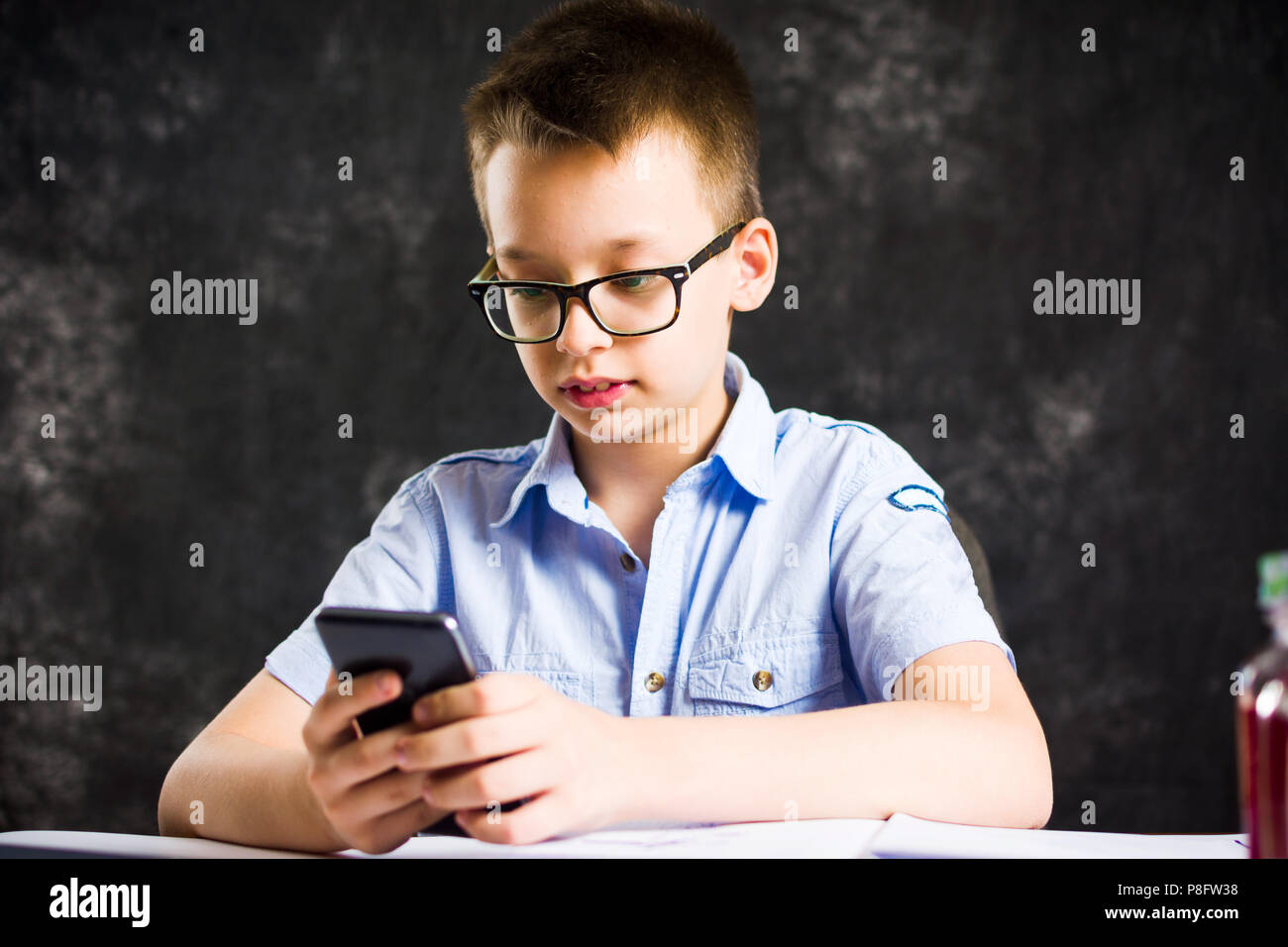 Junge spielt das Telefon während der Hausaufgaben zu Hause Stockfoto