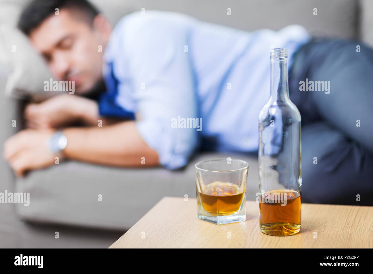 Flasche Alkohol am Tisch und schlafenden betrunkenen Mann Stockfoto