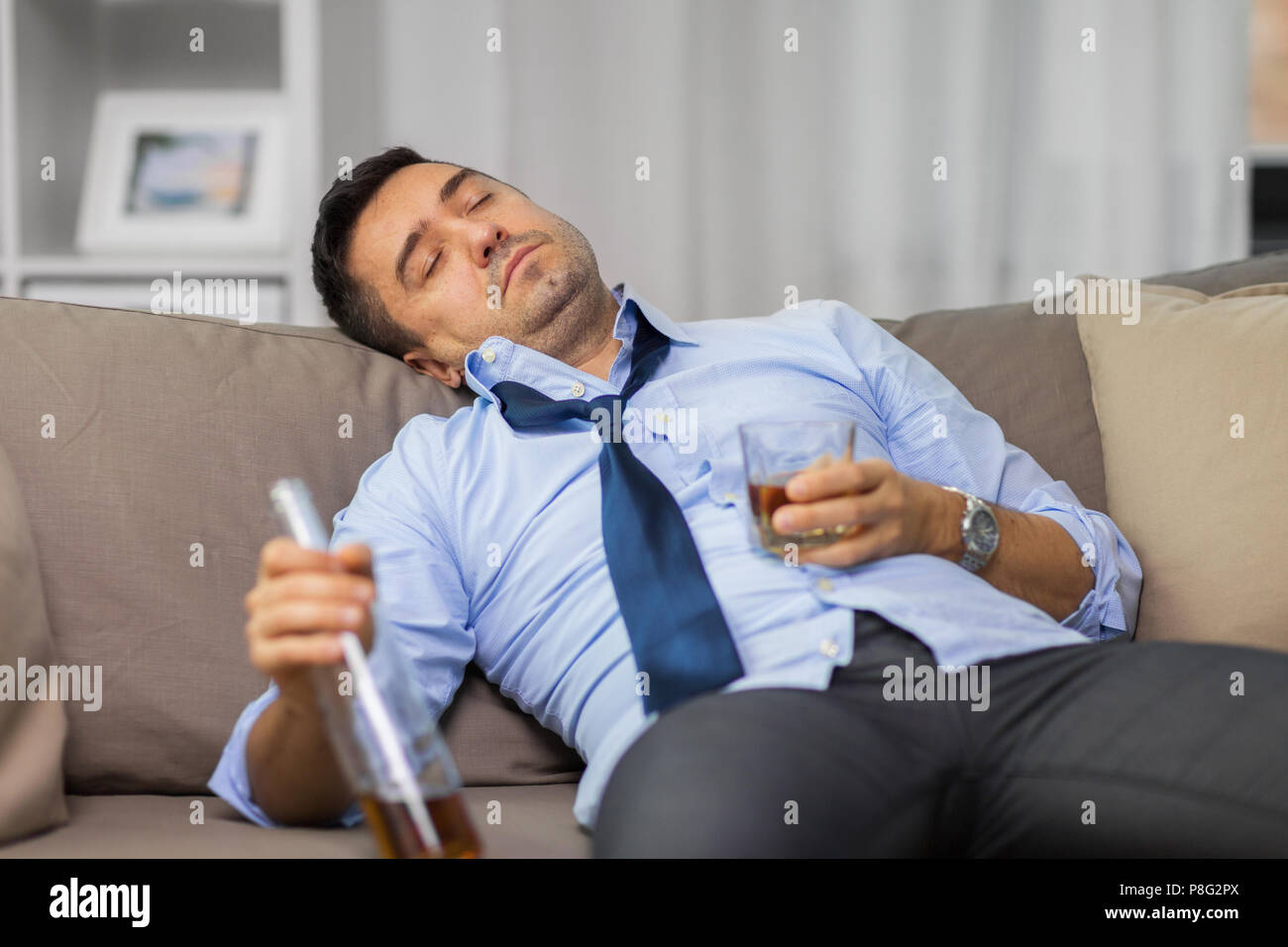 Betrunkener Mann mit Flasche Alkohol schlafen zu Hause Stockfoto