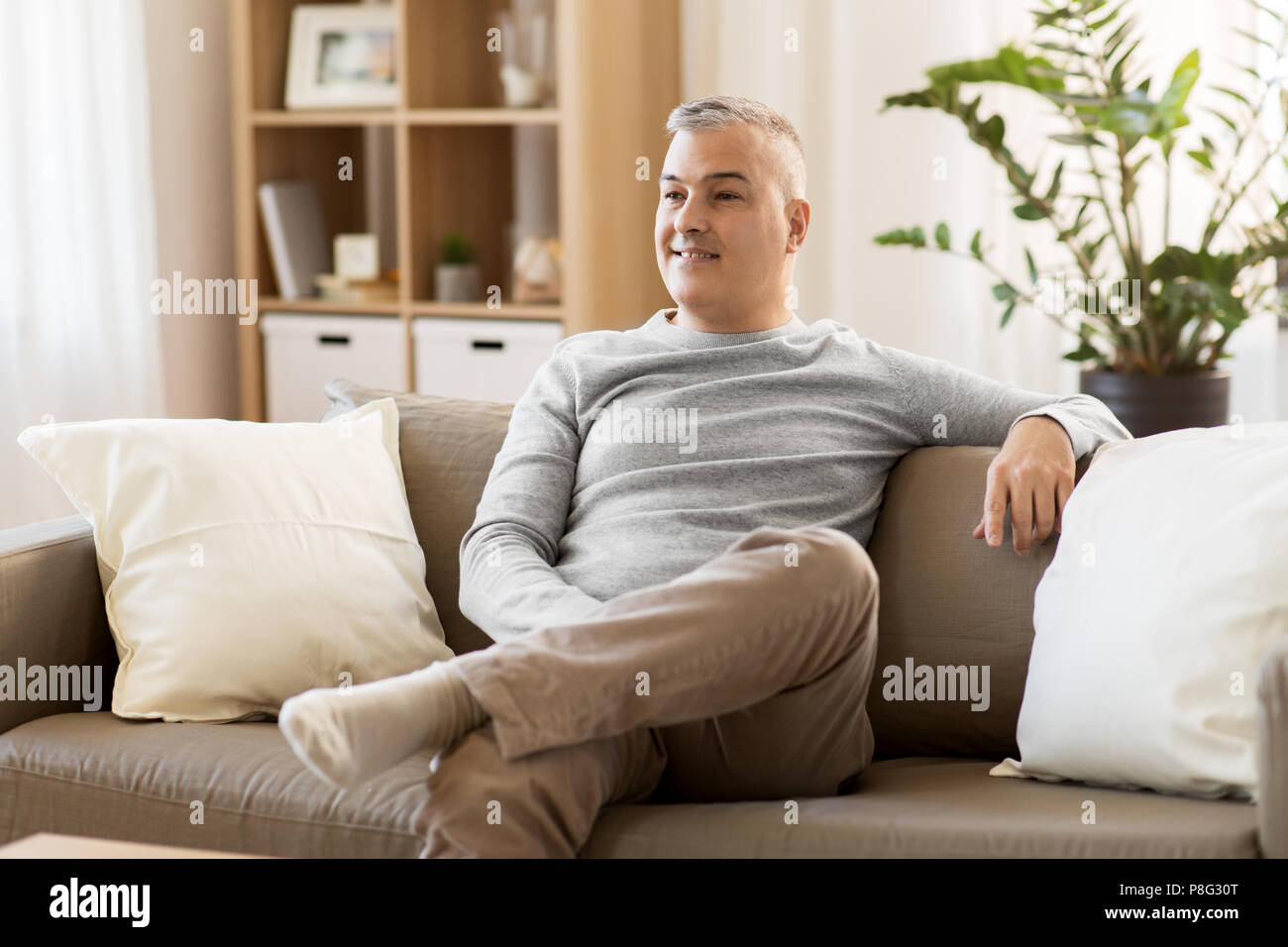 Glücklich Mann mittleren Alters auf dem Sofa zu Hause sitzen Stockfoto