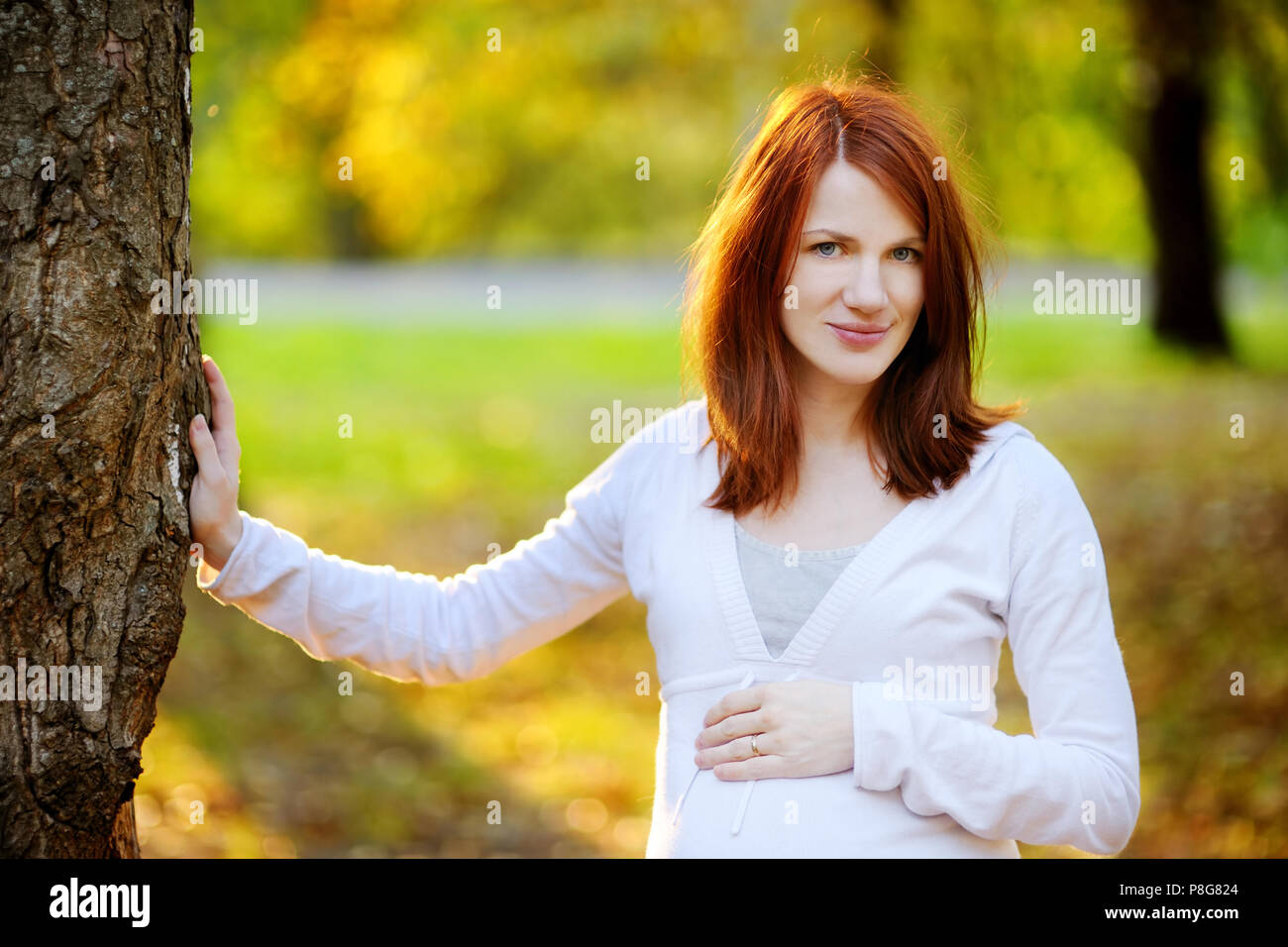 Schöne schwangere Frau im Herbst an einem Sonnenuntergang Stockfoto